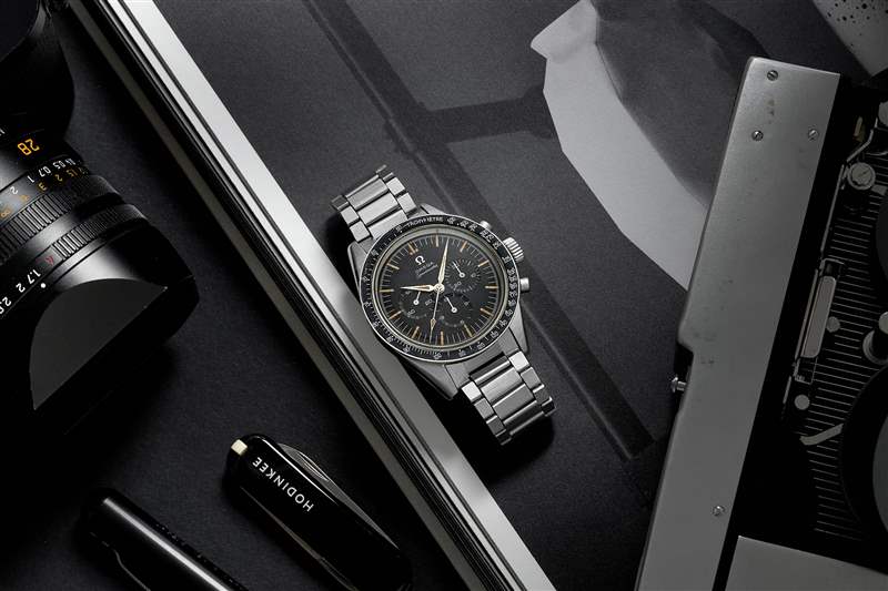 1960 年代 Omega Speedmaster Ref. 的生活方式圖片。 鋼手鏈上的 2998-6 旁邊是一本打開的書、一臺徠卡相機(jī)和一把黑色 HODINKEE 品牌的 Victorinox 瑞士軍刀。